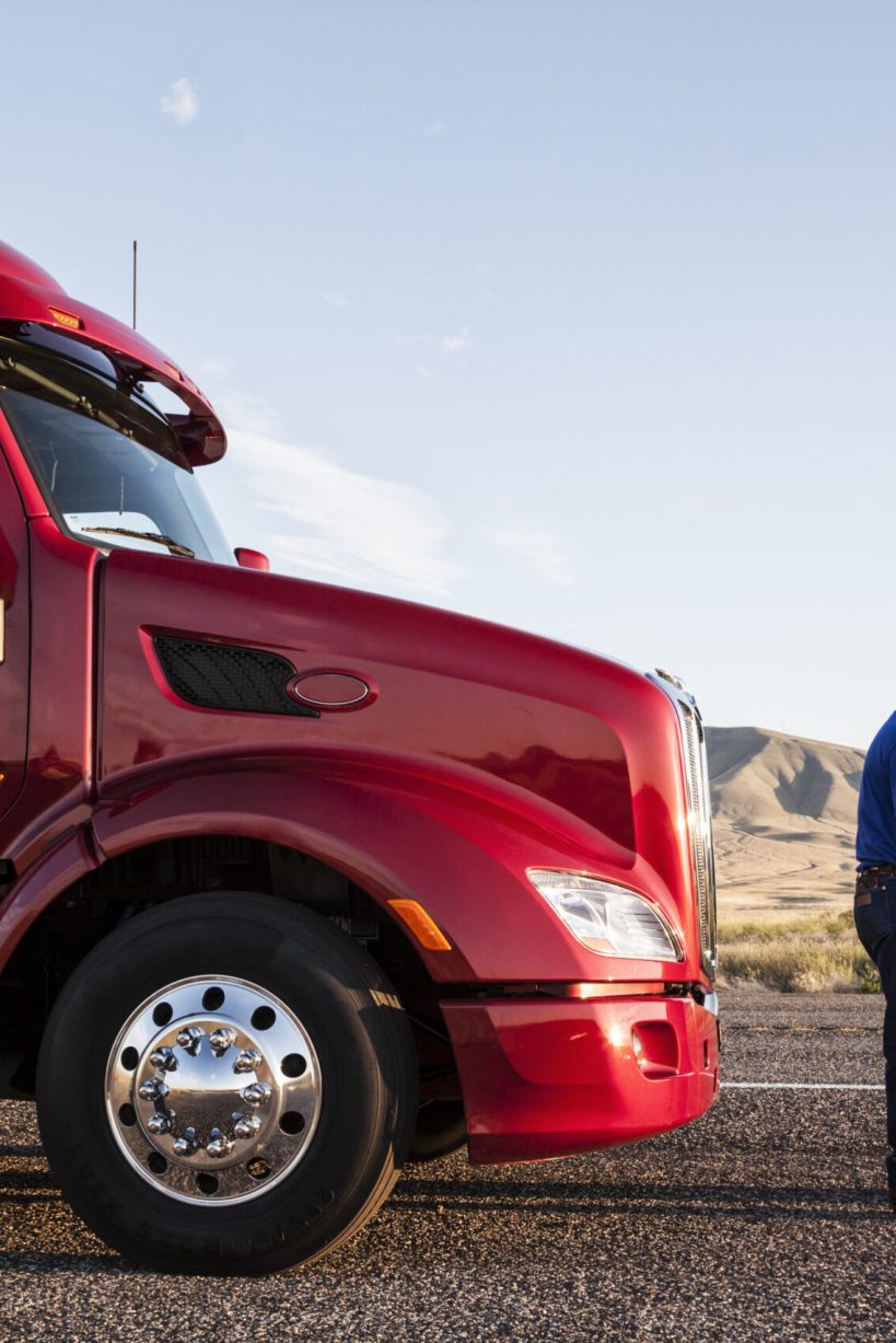 Husband and wife driving team checking their itinerary while standing in front of their commercial truck.