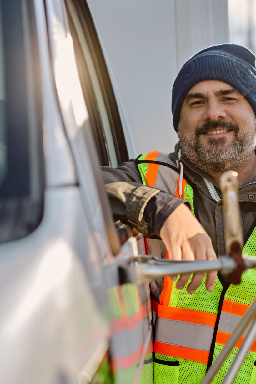 Happy professional driver by his truck before the ride looking at camera.